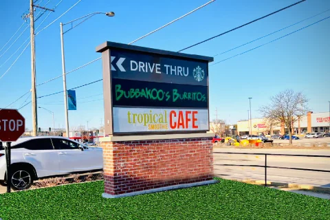 Pylon sign at Chicago shopping mall by SignFreaks, showing drive-through and multiple shops/cafes.
